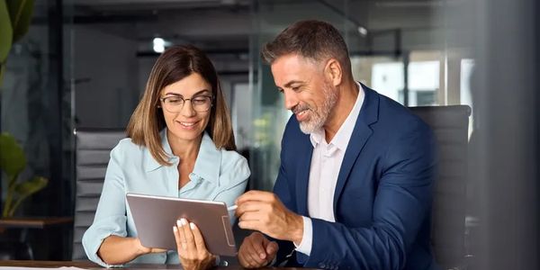 Two colleagues collaborating over a tablet in a modern office.
