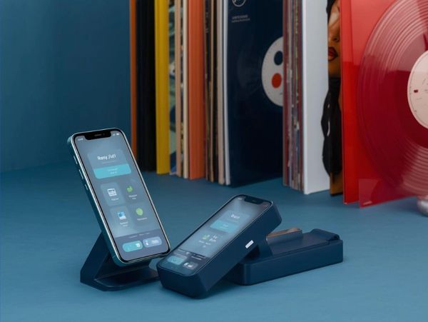 Two smartphones on angled stands displaying app interfaces on a blue table.