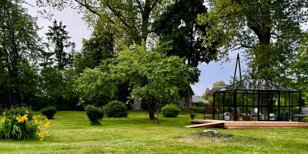 A peaceful garden with lush green grass and a glass gazebo.