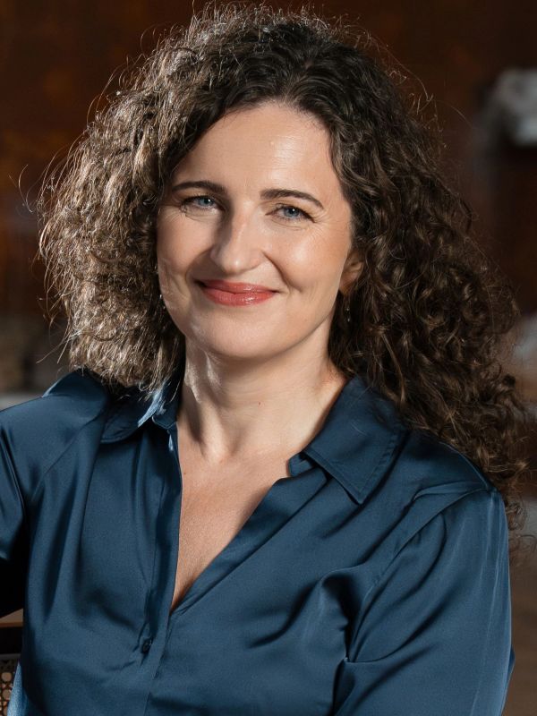 Smiling woman with curly hair in a blue shirt.