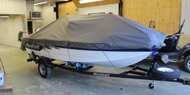 A covered MirroCraft boat on a trailer inside a garage.