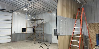 Interior of a spacious workshop with scaffolding, a ladder, and a partition curtain.