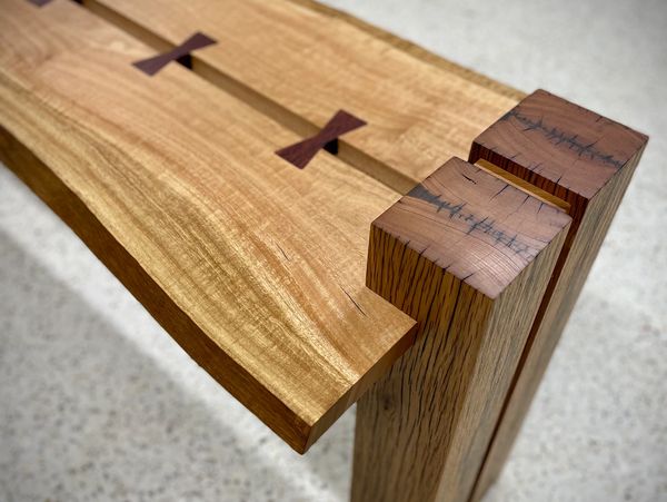 Close-up of a wooden bench joint with butterfly keys and solid legs.
