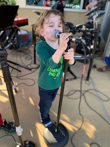Young boy singing on a microphone.