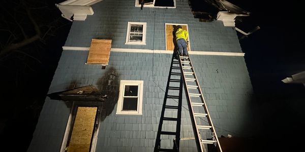 Person securing a window on a house at night.