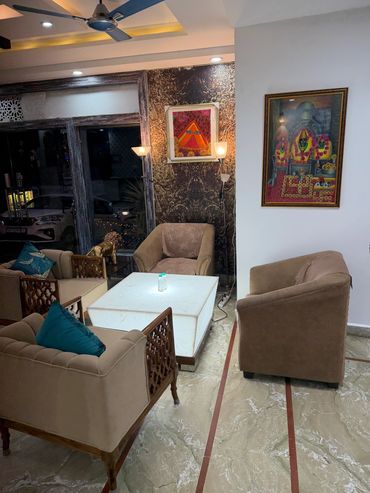 Cozy living room with beige chairs, modern lighting, and colorful artwork on the walls.