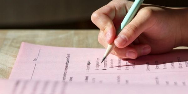 Closeup of a child's hand holding a pencil while taking a standardized exam