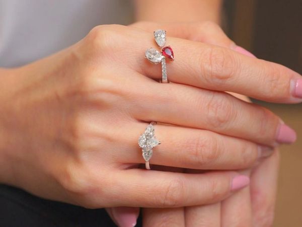 Two elegant rings with diamonds and a ruby on a woman's hand.