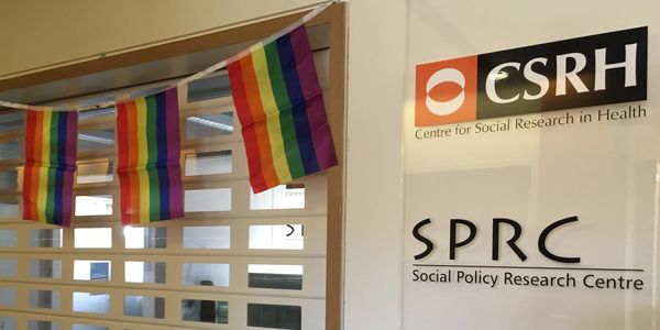 Image of Centre for Social Research in Health's reception desk, framed by rainbow flags.