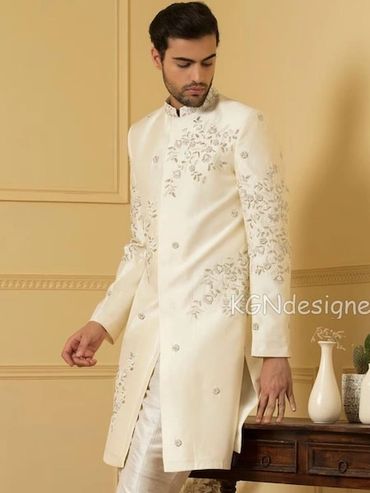 Man wearing elegant cream sherwani with intricate embroidery.