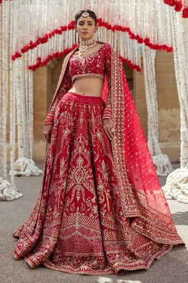 Woman in an ornate red bridal lehenga with intricate embroidery.