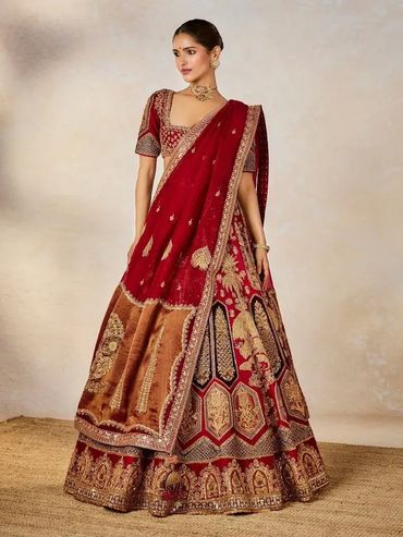 Woman in an elegant red and gold traditional lehenga with intricate embroidery.