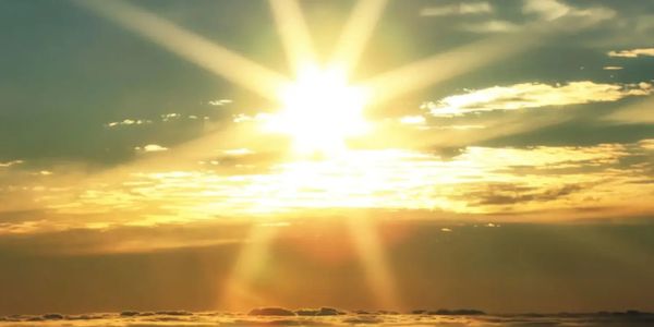 Bright sun shining over a cloudy horizon at sunset.