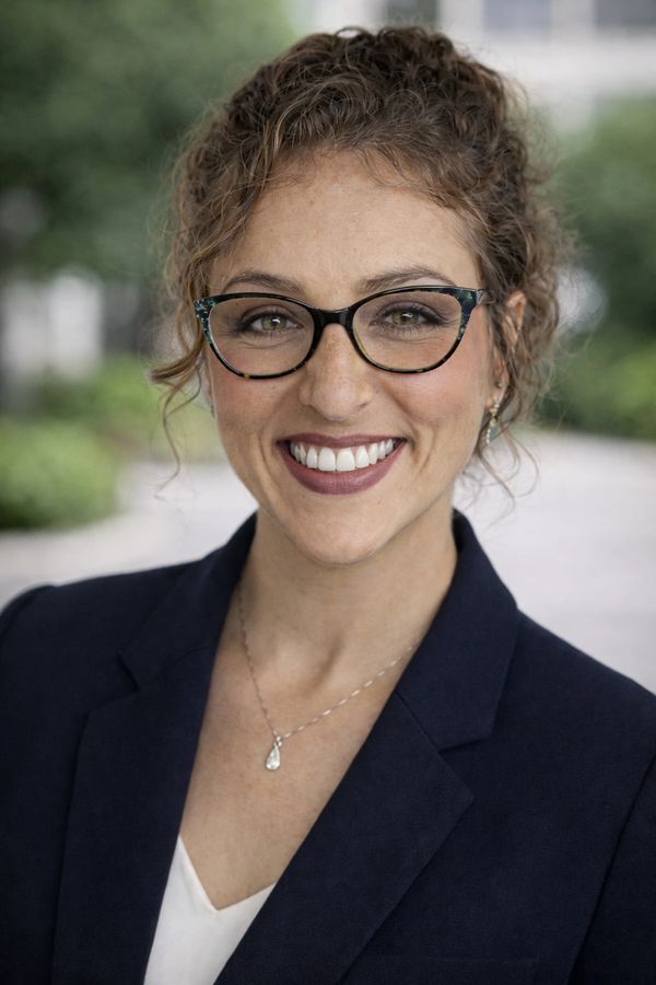 Smiling woman with glasses in business attire.