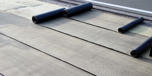  rolls of single ply membrane roofing material on a flat roof being installed