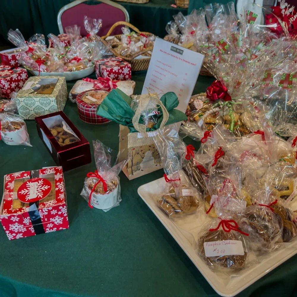 Table filled with festive wrapped cookies and treats for sale.