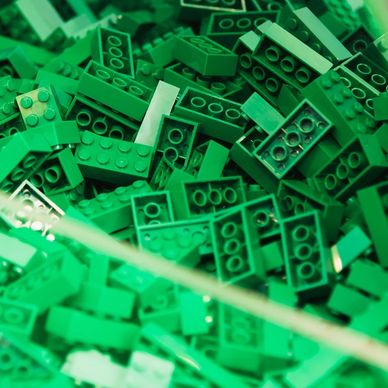 Pile of green LEGO bricks scattered together.