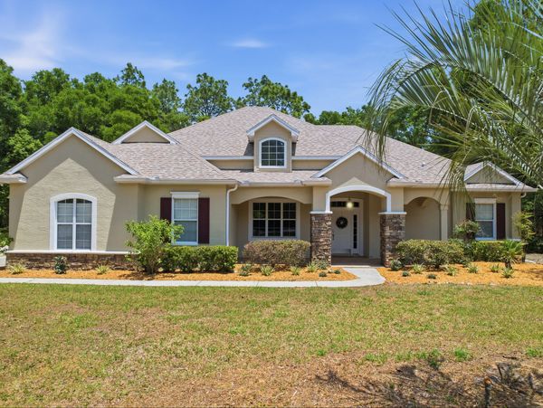 Beautiful beige suburban house with a spacious front yard under a clear blue sky.
