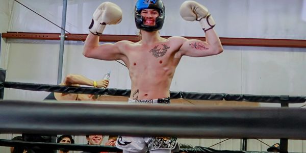 Boxer celebrating victory in the ring with gloves and helmet.
