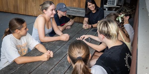 Group of young people having a conversation around a wooden table.