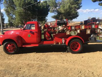 Vintage red fire truck with decorations outdoors.