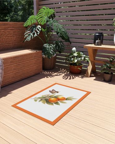 Cozy outdoor seating area with plants and a decorative orange-themed mat.