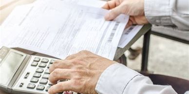 Person using calculator and holding documents.