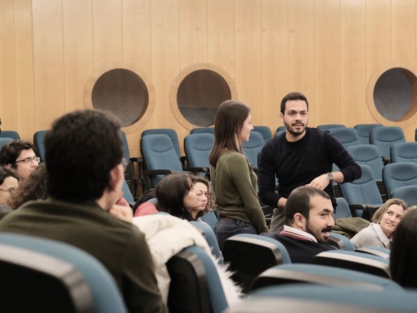 People engaged in conversation in a lecture hall.