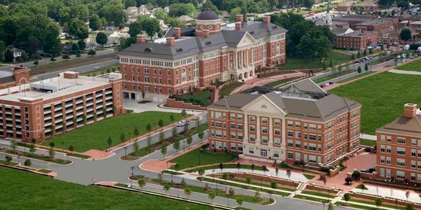 Aerial view of a large university campus with multiple brick buildings and green spaces.