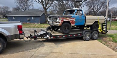 Vintage truck with multi-color panels on a trailer.
