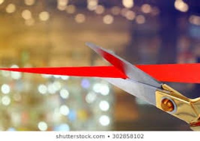 Close-up of scissors cutting a red ribbon.