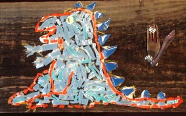 A mosaic dinosaur made with broken tiles on a wooden surface.