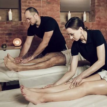 Couple receiving leg massages in a cozy spa setting.