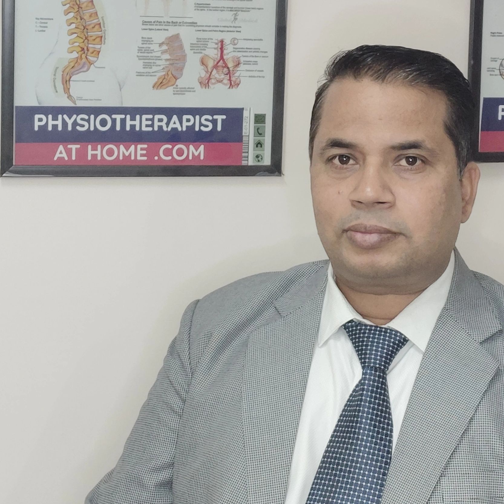 Professional man in suit with physiotherapy posters in the background.