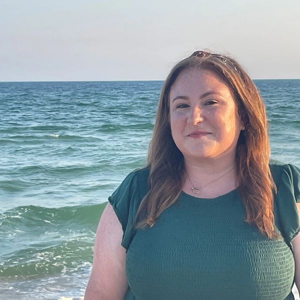 Woman smiling by the ocean on a sunny day.