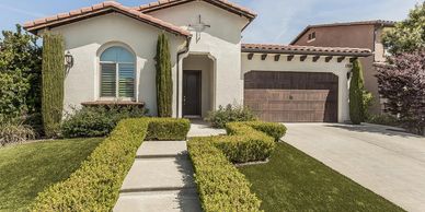 Single-story house with manicured hedges and a tiled roof.