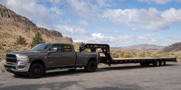 RAM truck towing a large flatbed trailer in a desert landscape.