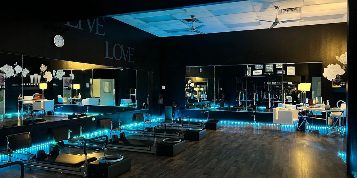 A modern pilates studio with reformer machines and blue LED lighting.