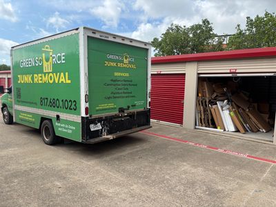 Green Source Junk Removal truck next to storage unit that’s filled with junk. 