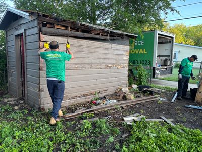 Two Green Source Junk Removal employees taking down a shed in Fort Worth, Tx. 