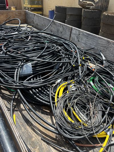 A large pile of coiled black cables with some yellow and green ones mixed in.