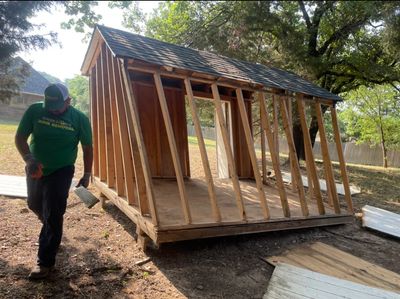 Green Source Junk Removal employee tearing down shed. 