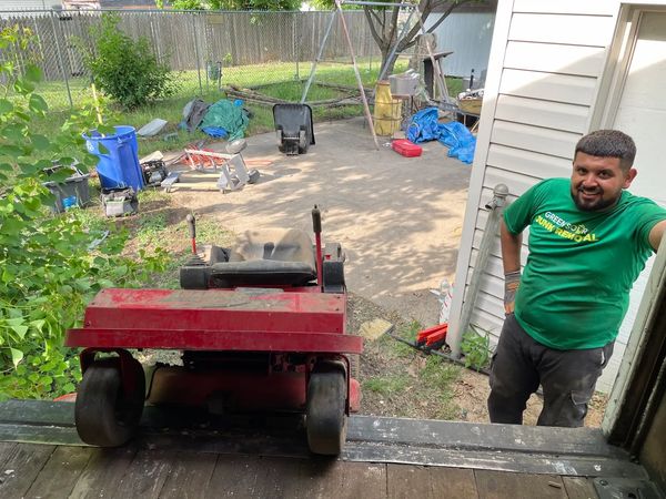 Employees loading a riding lawn mower onto truck/