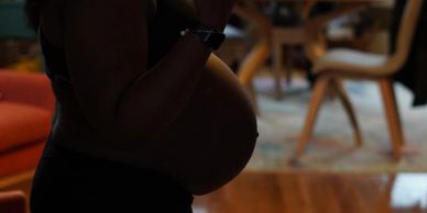 Profile of pregnant woman standing with elbows down, hands lifted.