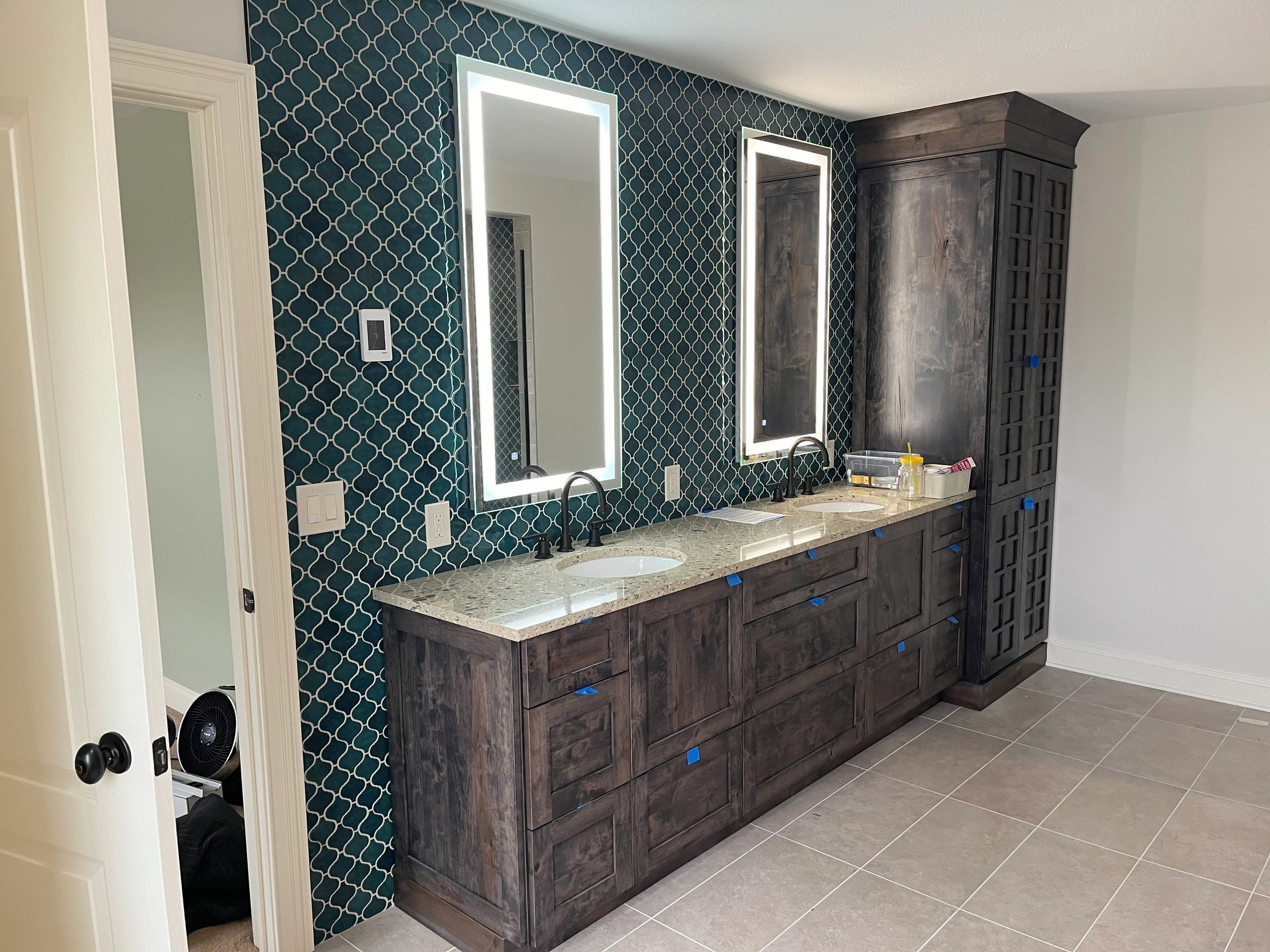 Modern bathroom with illuminated mirrors and dark wood cabinetry.
