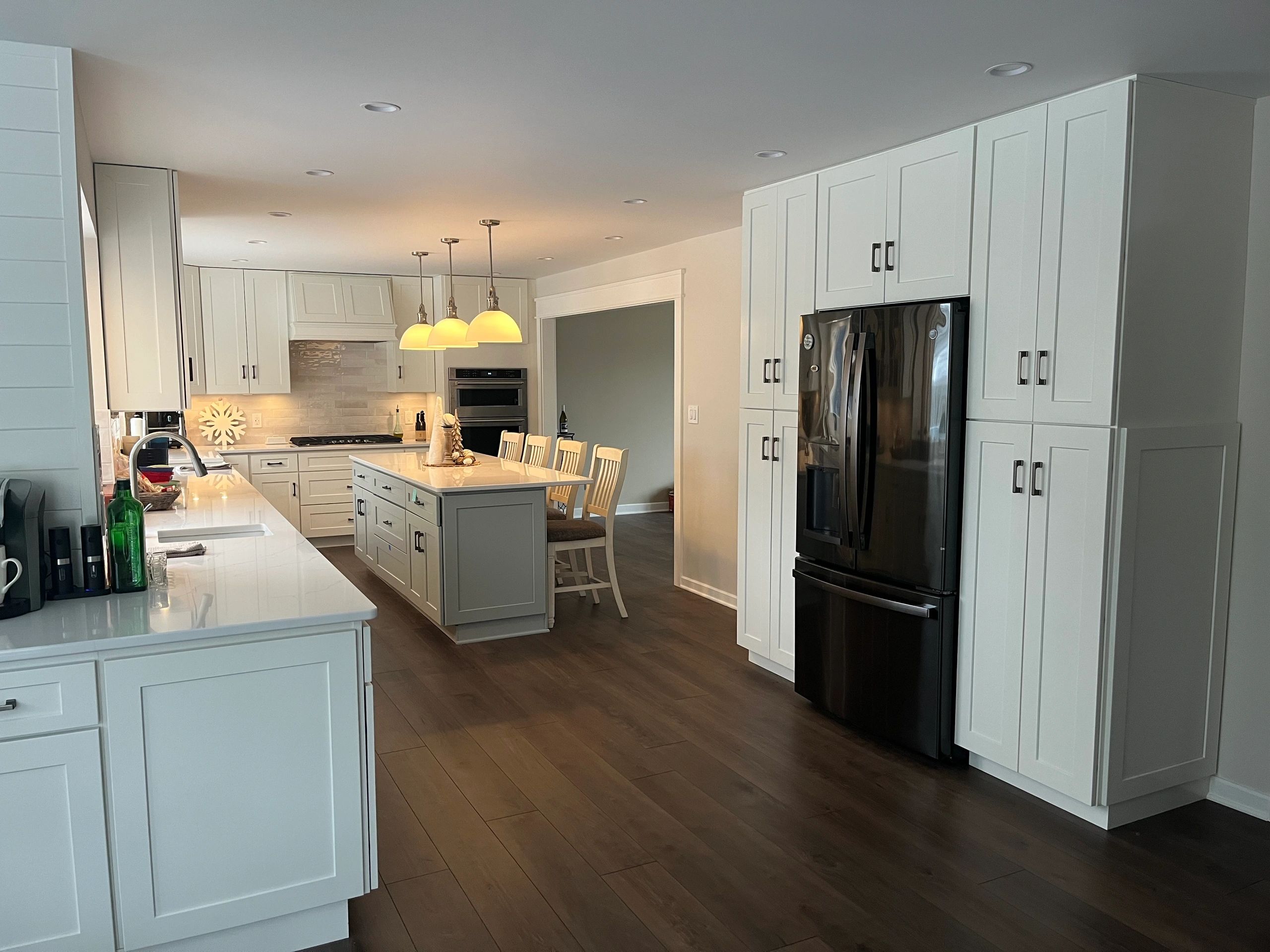 Modern kitchen with white cabinets and black refrigerator.