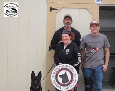 Three people and a dog posing with a K9 search and rescue sign.