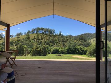 View of green hills from a shaded porch.