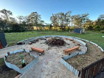 Outdoor campfire area with benches and garden beds.