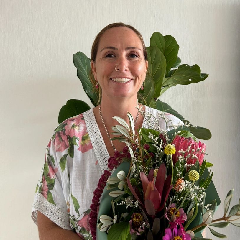 Smiling woman holding a colorful bouquet of flowers indoors.